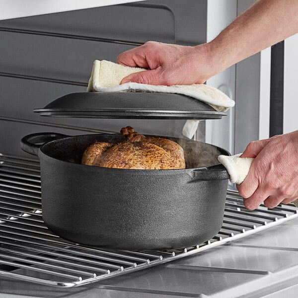 A person putting a chicken in a Valor cast iron dutch oven.