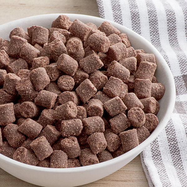 A bowl of brown square shaped food on a table.