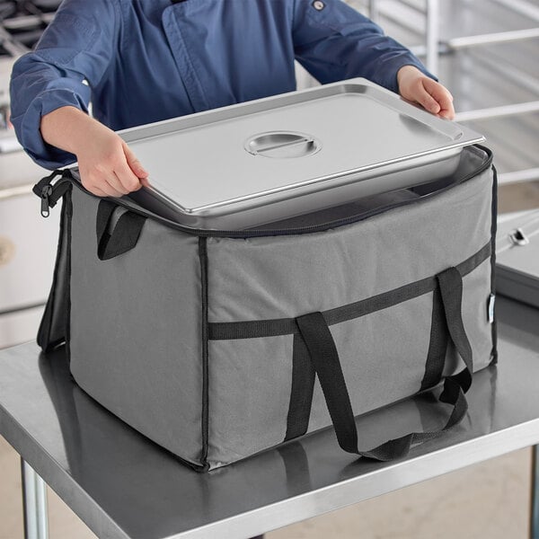 A woman holding a large gray Choice insulated cooler bag.