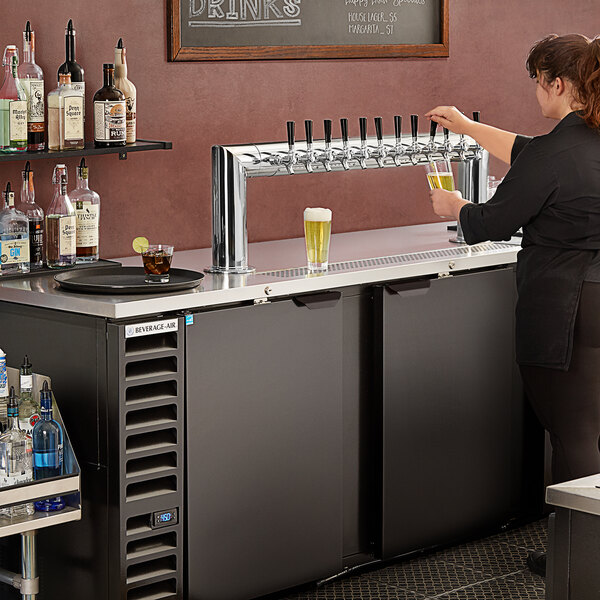 A woman using a Beverage-Air 12 tap kegerator to pour wine.