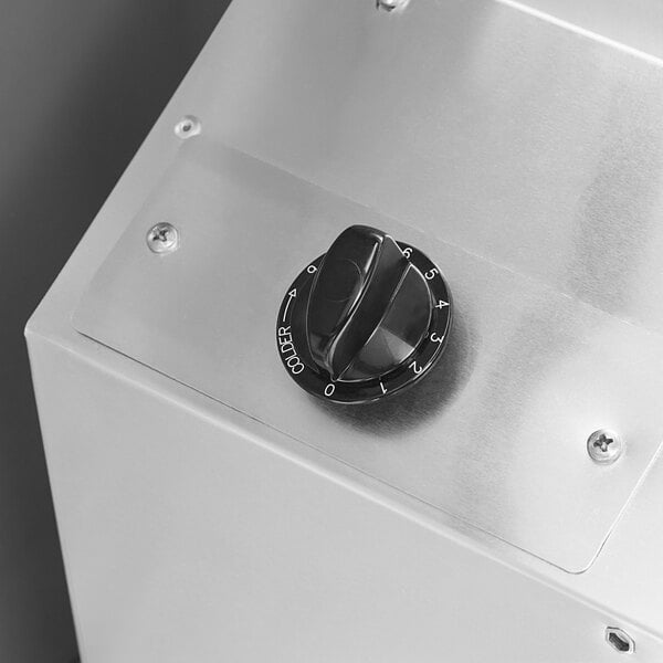 A silver metal box with a black dial and black knobs.