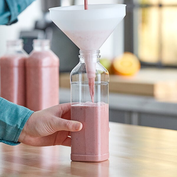 A person pouring pink liquid into a Square PET clear juice bottle.