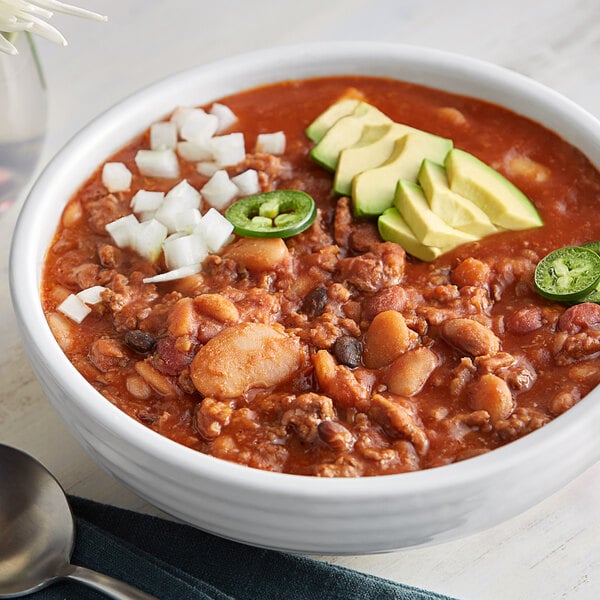 A bowl of Bob's Red Mill 13-Bean Soup with vegetables and meat next to a spoon.