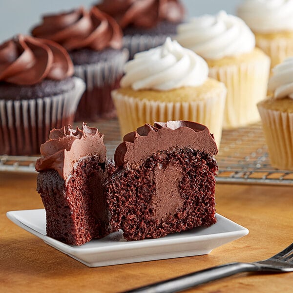 A chocolate cupcake with white frosting on a plate with a bite taken out of it.