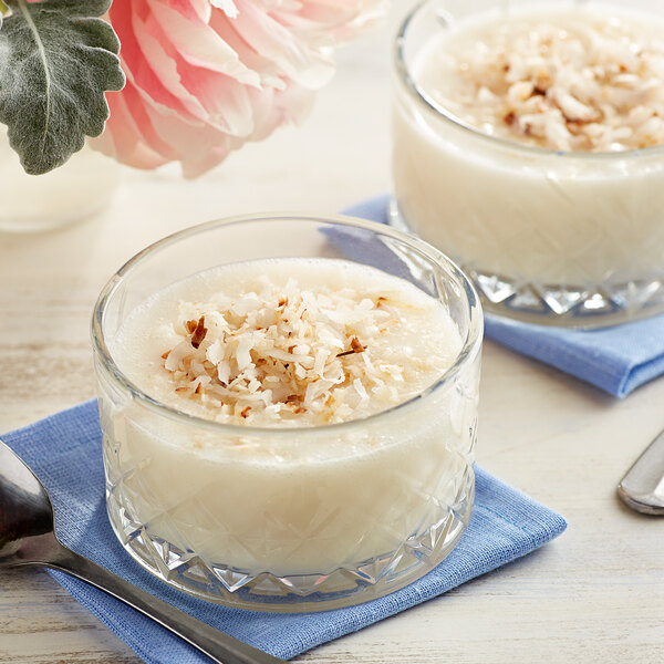 A glass bowl filled with cream of coconut dessert topped with shredded coconut.