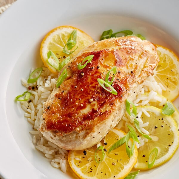 A plate of food with rice, chicken, and a lemon slice.