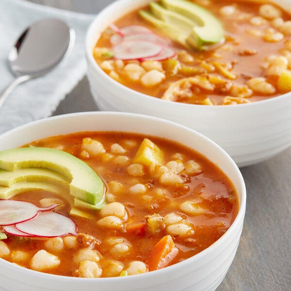 Two bowls of Goya white hominy soup with vegetables and meat.