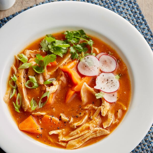 A bowl of soup with chicken, radishes, and carrots with Maggi Jugo seasoning sauce.