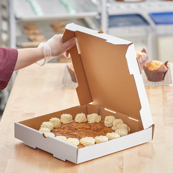 A person holding a Choice white corrugated bakery box filled with food.