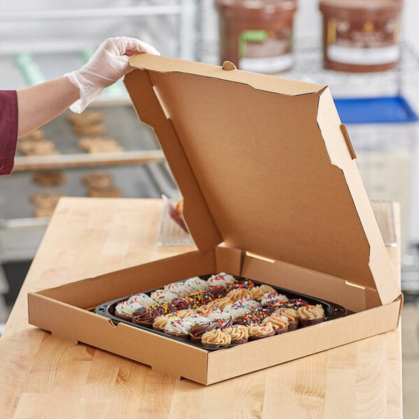 A person holding a Choice Kraft bakery box full of cupcakes.