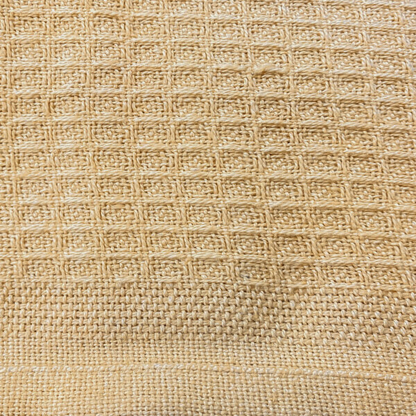 A close-up of a beige woven fabric with a honeycomb pattern.