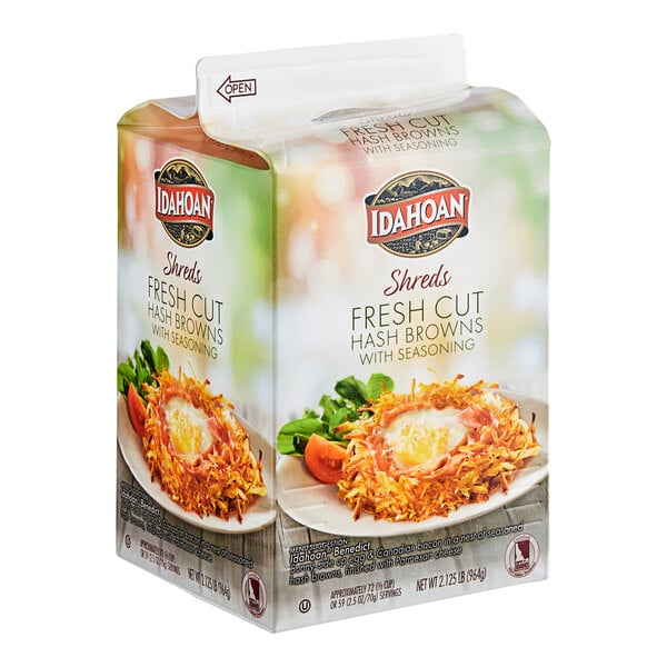 A carton of Idahoan Shreds Fresh Cut Hash Browns on a plate of food.