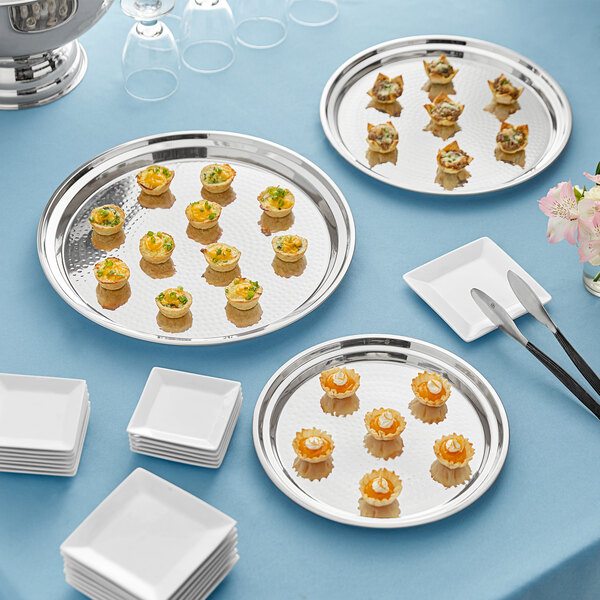 A group of Acopa stainless steel catering trays and white plates with food on them.