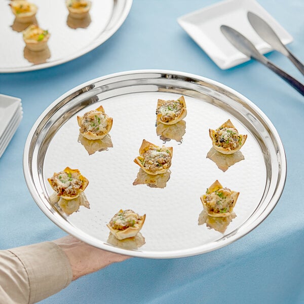 A hand holding an Acopa stainless steel catering tray with food on it.