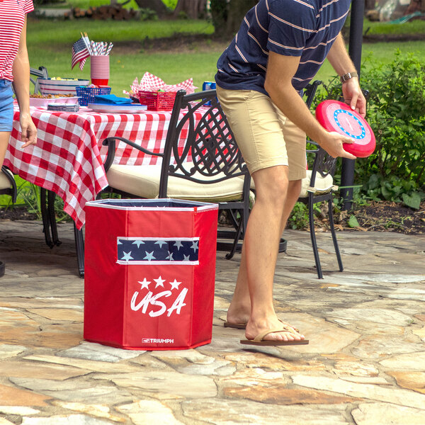 A man and woman play frisbee with a red and white patriotic Disc Flyerz game.