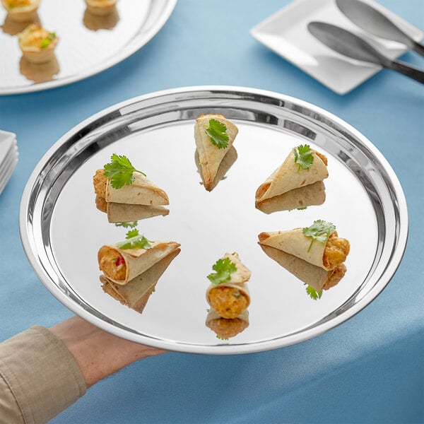 A person's hand holding an Acopa stainless steel catering tray with food on it.
