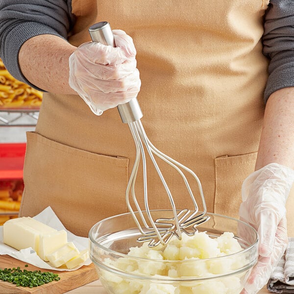 A person using a Fox Run stainless steel 2-in-1 round-faced potato masher to mix mashed potatoes.