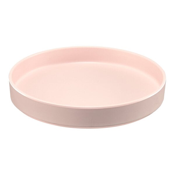 A round, blush-colored melamine plate with a raised rim.