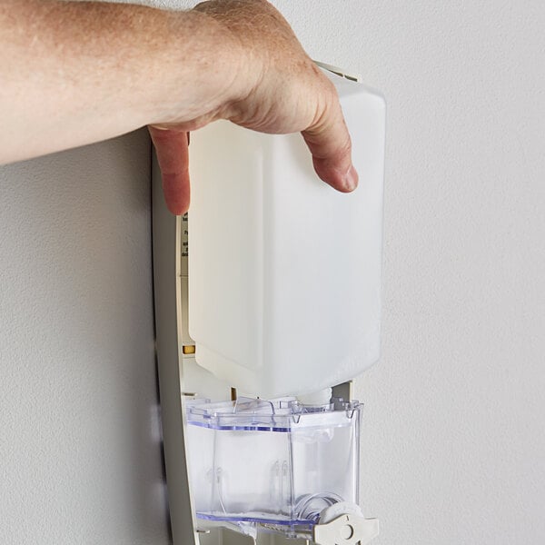 A hand pushing a Dial Sensitive Skin hand soap refill into a dispenser.