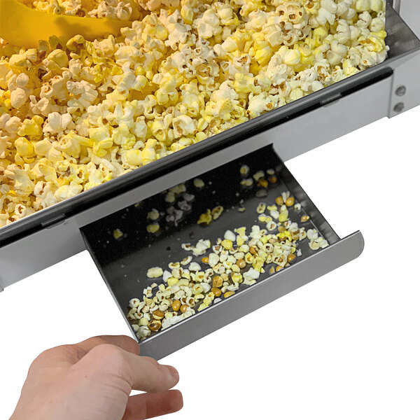 A hand using a Paragon Mod Pop popcorn machine to fill a container with popcorn.