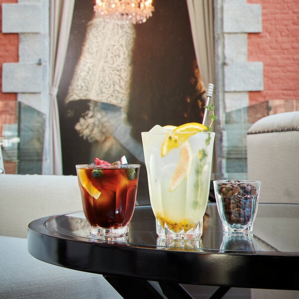 Arcoroc highball glasses filled with liquid and ice on a table