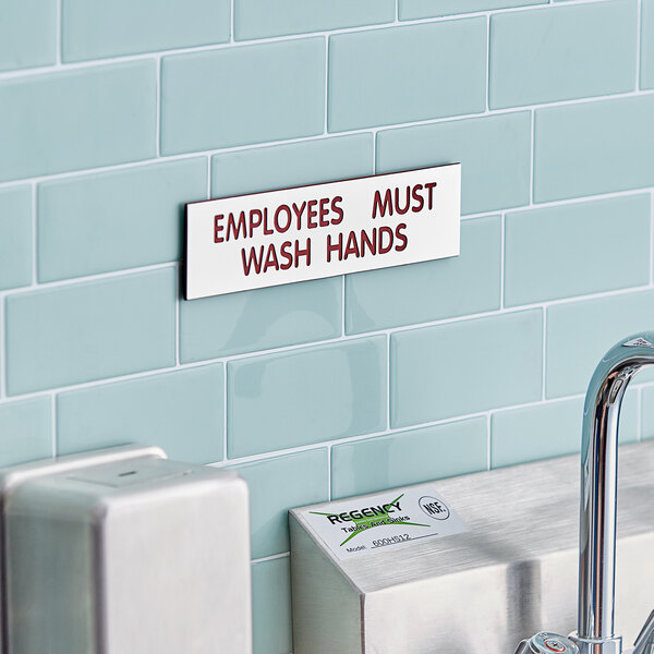 A white and red Cosco "Employees Must Wash Hands" sign on a wall.