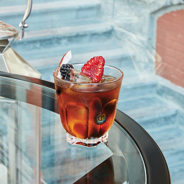An Arcoroc Arcadie rocks glass with ice tea, berries, and ice on a table.