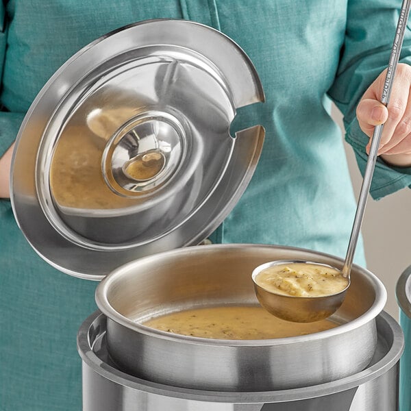 A woman using a Vollrath stainless steel inset pot to serve soup with a ladle.