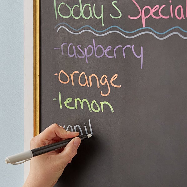 A hand writing with Dri Mark chalk markers on a chalkboard.