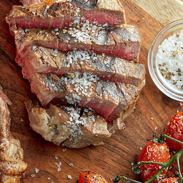 A piece of steak with Badia Black Truffle Sea Salt on a wooden surface.
