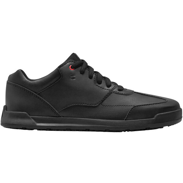 A black Shoes For Crews women's athletic shoe with red accents.