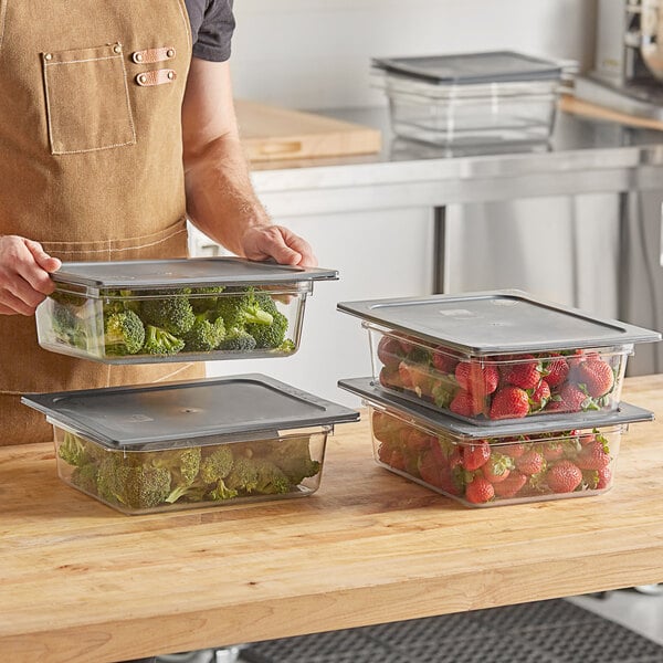 A man holding a box of Vigor clear plastic food pans with broccoli inside.