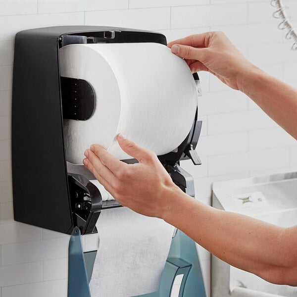 A person holding a roll of Lavex white hardwound paper towels.