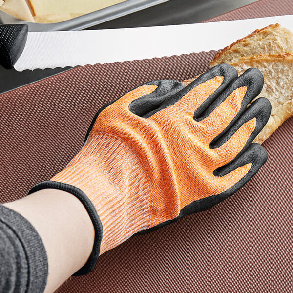 a hand wearing a glove holding a piece of bread