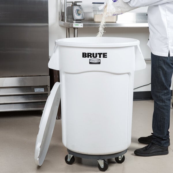 A man pouring flour into a white Rubbermaid ingredient storage bin.