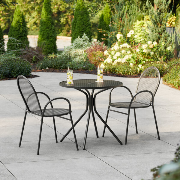 A Lancaster Table & Seating Harbor black table with 2 chairs on a patio.