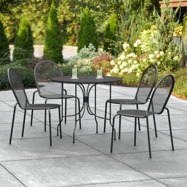 A Lancaster Table & Seating Harbor black outdoor table with chairs on a patio.