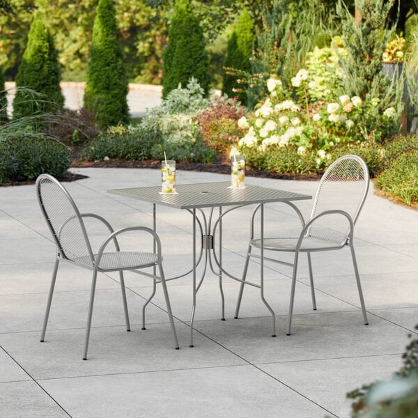 A Lancaster Table & Seating Harbor Gray table and chairs on a patio.