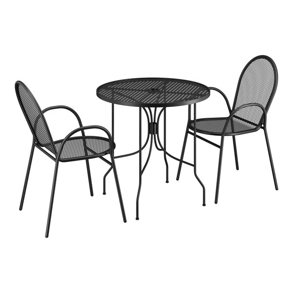 A Lancaster Table & Seating Harbor black metal bistro set with ornate legs on an outdoor patio with two chairs.