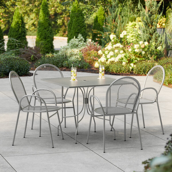 A Lancaster Table & Seating Harbor Gray outdoor table and chair set on a patio.