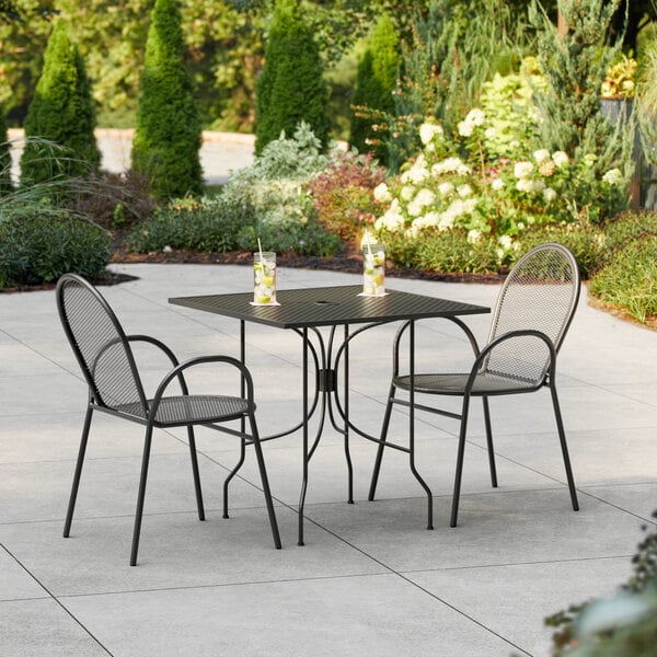 A Lancaster Table & Seating Harbor Black table and chairs on a patio.