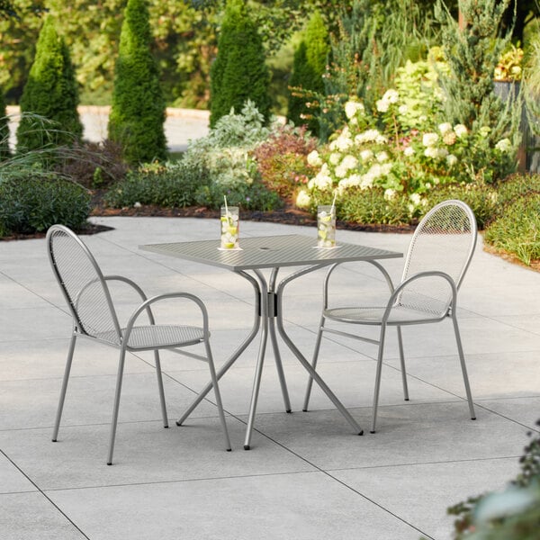 A Lancaster Table & Seating Harbor Gray square outdoor table with chairs on a patio.