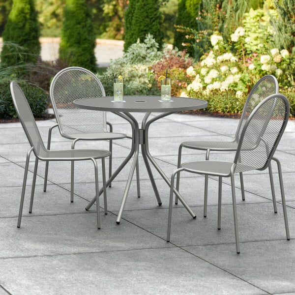 A Lancaster Table & Seating Harbor Gray outdoor table and chairs on a patio.