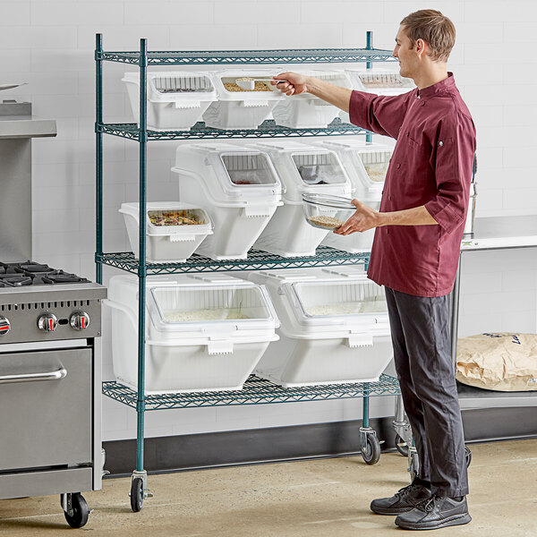 A man standing in a kitchen with a white Baker's Lane ingredient bin filled with food.