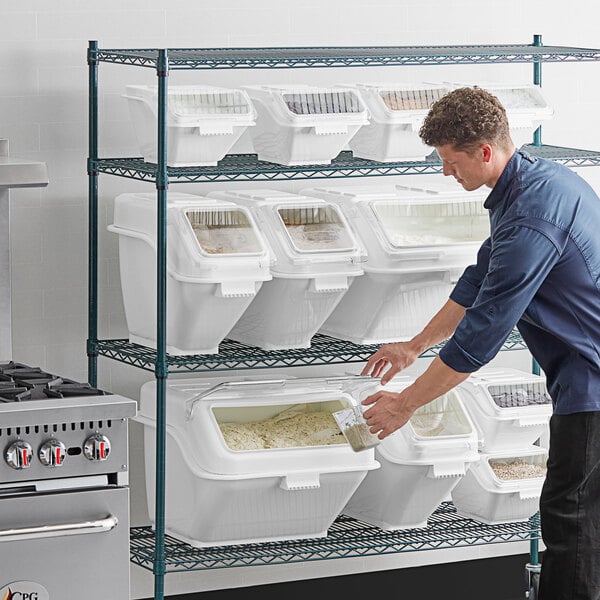 A man putting food in a white plastic container with a lid.