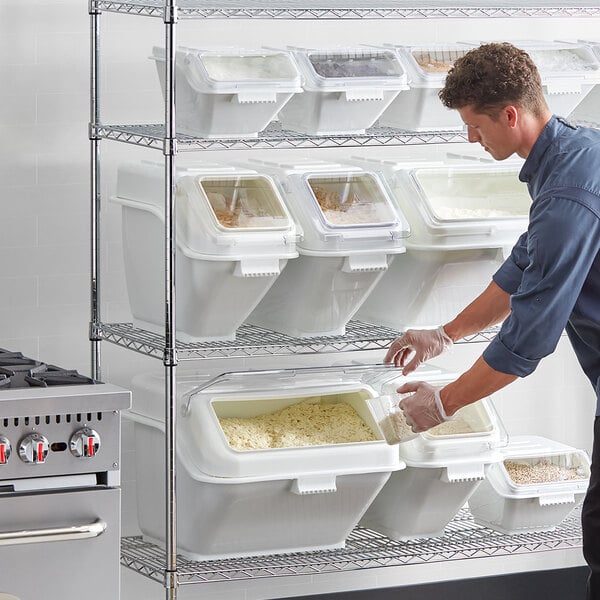 A man putting food into white Baker's Lane shelf bins.