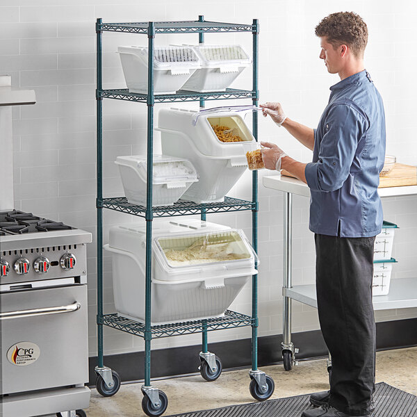 A man in a professional kitchen using a white Baker's Lane ingredient bin to store food.