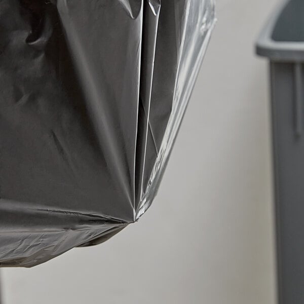 A Lavex Hercules black plastic trash bag on a trash can.