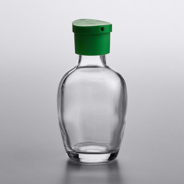 a clear glass bottle with a green cap