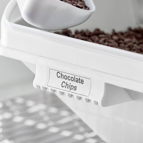 A white Baker's Mark ingredient bin with a white scoop of chocolate chips.